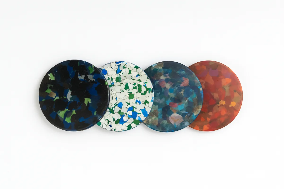 Four round Plaskito prototypes in recycled plastic, with blue, green, white and red patterns